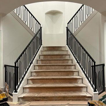 Black vertical metal stair railings installed in a contemporary interior space.